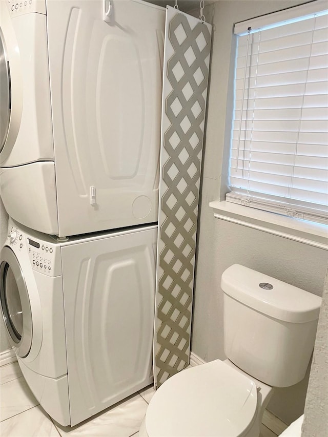 bathroom with toilet and stacked washer / dryer