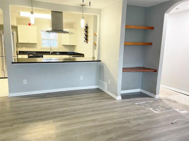 kitchen with visible vents, island range hood, dark countertops, wood finished floors, and white cabinetry