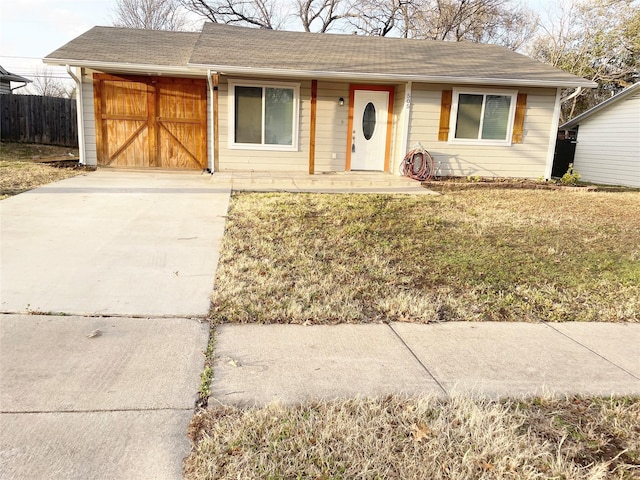 single story home featuring driveway, fence, a front lawn, and roof with shingles