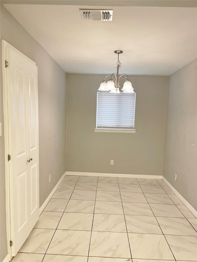 spare room featuring visible vents, a notable chandelier, and baseboards