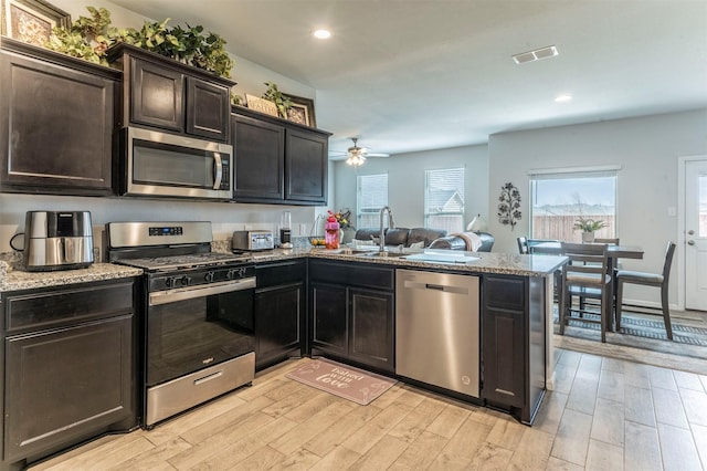 kitchen featuring stainless steel appliances, visible vents, light wood-style flooring, a sink, and a peninsula