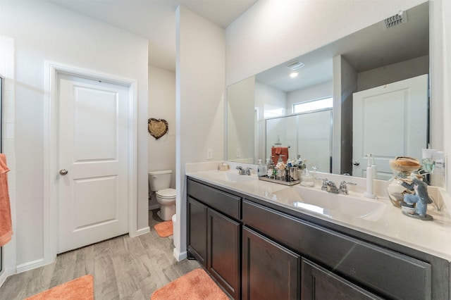 full bathroom featuring visible vents, toilet, wood finished floors, a shower stall, and a sink