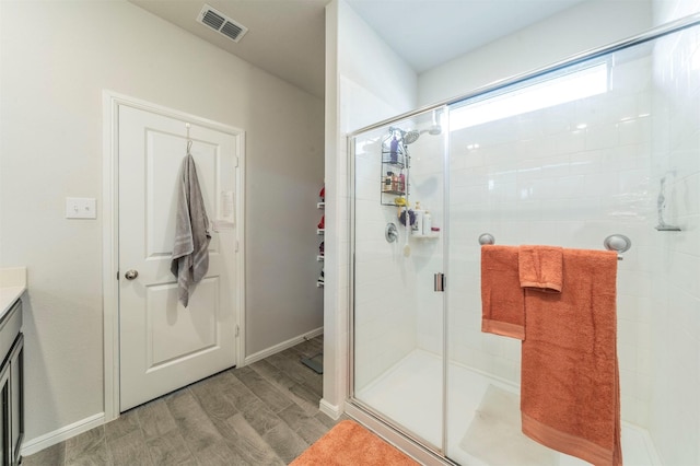 bathroom with visible vents, a stall shower, vanity, wood finished floors, and baseboards