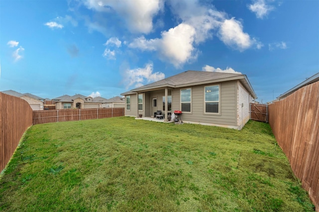 back of property with a yard, a patio, and a fenced backyard