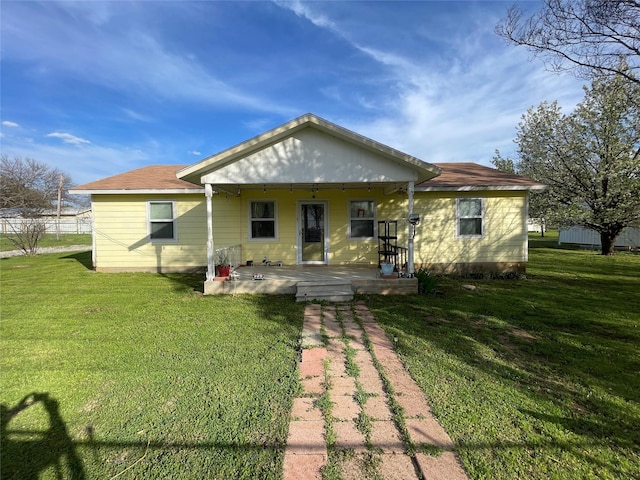 rear view of property featuring covered porch and a yard