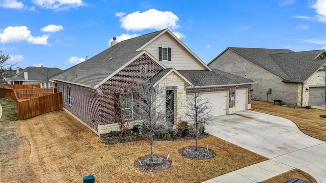 view of front facade with a shingled roof, concrete driveway, fence, a garage, and stone siding