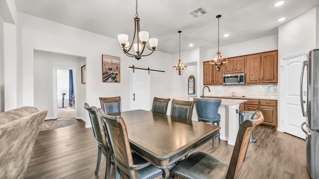 dining area featuring a barn door, visible vents, wood finished floors, a chandelier, and recessed lighting