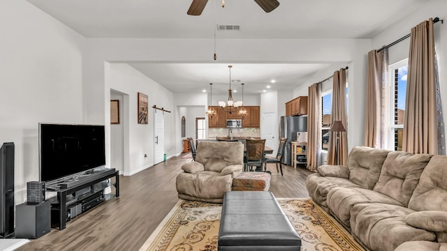 living room featuring a healthy amount of sunlight, a barn door, visible vents, and wood finished floors