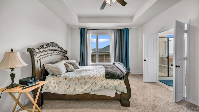 bedroom featuring baseboards, a tray ceiling, a ceiling fan, and light colored carpet