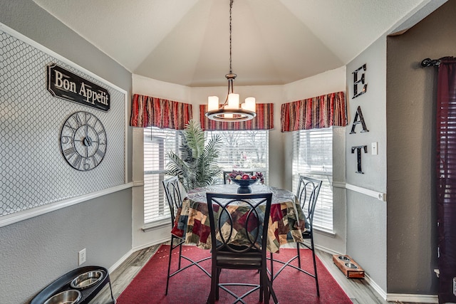 dining area with lofted ceiling, an inviting chandelier, baseboards, and wood finished floors