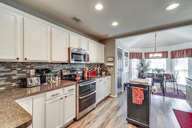 kitchen featuring visible vents, backsplash, appliances with stainless steel finishes, light wood-style floors, and white cabinets