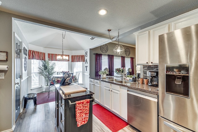 kitchen with decorative backsplash, white cabinetry, stainless steel appliances, and wood finished floors