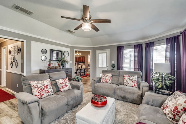 living area featuring a ceiling fan, a tray ceiling, visible vents, and wood finished floors