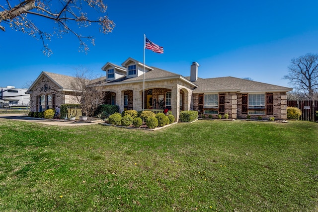 view of front of house with a shingled roof, brick siding, fence, and a front lawn