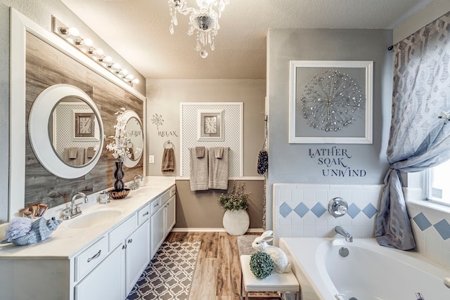 bathroom with double vanity, a garden tub, a textured ceiling, and a sink