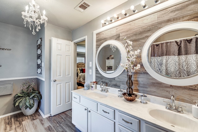 bathroom with wood finished floors, visible vents, a sink, and double vanity