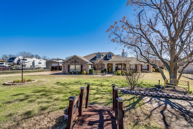 view of front of house featuring brick siding, fence, and a front yard