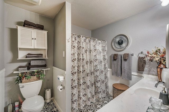 full bath with toilet, a textured ceiling, a sink, and a shower with shower curtain