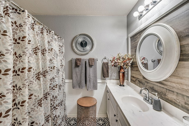 bathroom with a shower with curtain, a textured wall, a textured ceiling, and vanity