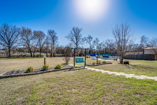 view of playground with fence, a fenced in pool, and a yard