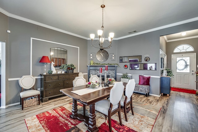 dining area featuring a chandelier, wood finished floors, visible vents, baseboards, and ornamental molding