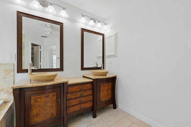 full bathroom with double vanity, tile patterned flooring, a sink, and baseboards