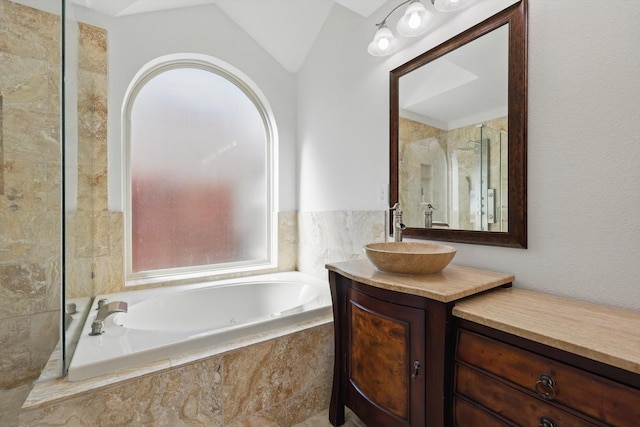 full bathroom featuring vaulted ceiling, a stall shower, vanity, and a bath