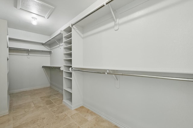 spacious closet with stone finish flooring and attic access