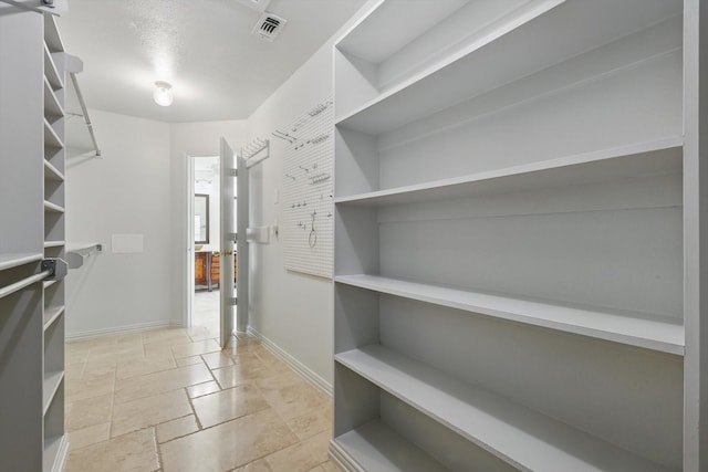 walk in closet with visible vents and stone tile floors