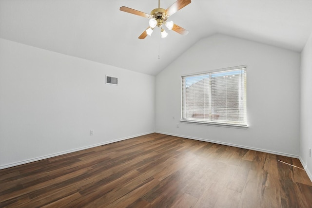 spare room featuring baseboards, visible vents, a ceiling fan, dark wood-style flooring, and vaulted ceiling