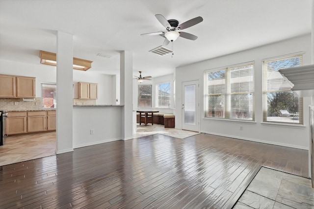 unfurnished living room with light wood-style floors, visible vents, ceiling fan, and baseboards