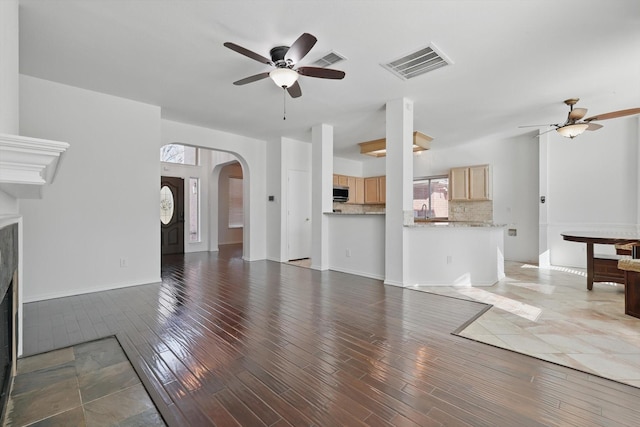 unfurnished living room featuring wood finished floors, visible vents, and a ceiling fan