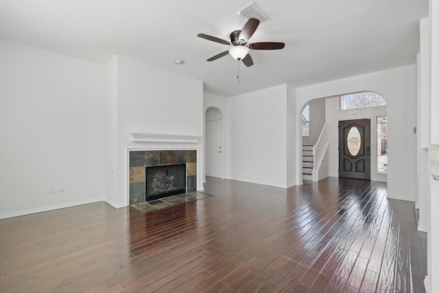 unfurnished living room featuring a ceiling fan, visible vents, a fireplace, and wood finished floors