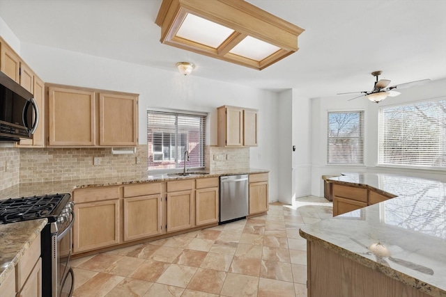 kitchen with light stone countertops, stainless steel appliances, backsplash, and light brown cabinetry