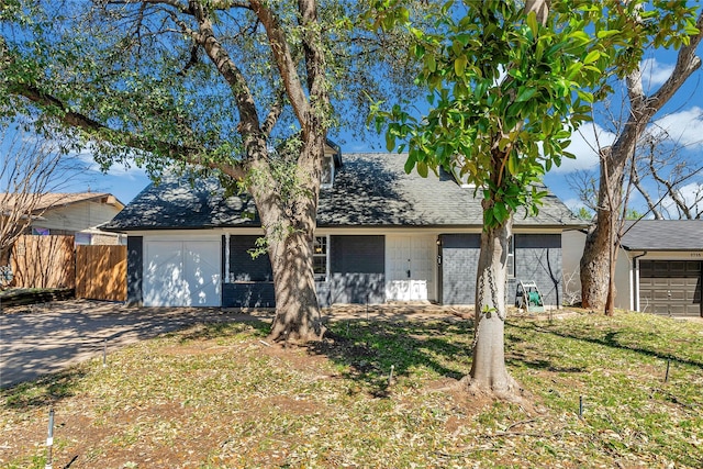 view of front of home with a garage, brick siding, and fence