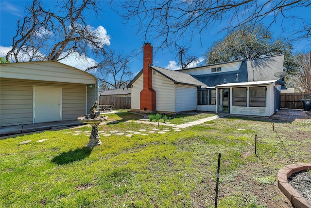 back of property featuring a lawn, a chimney, an outdoor structure, and fence