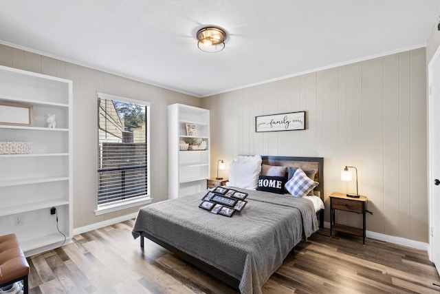 bedroom featuring baseboards, wood finished floors, and ornamental molding