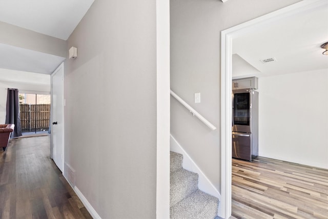 stairway featuring wood finished floors, visible vents, and baseboards