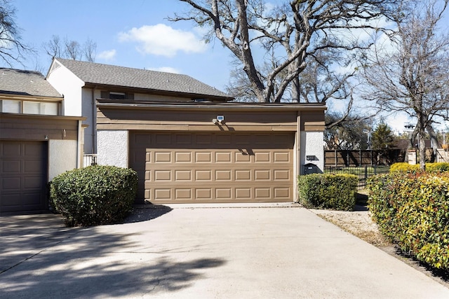 garage featuring driveway and fence