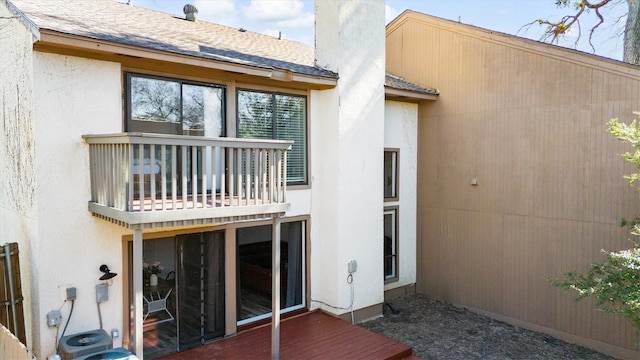 rear view of property featuring roof with shingles, a balcony, and stucco siding