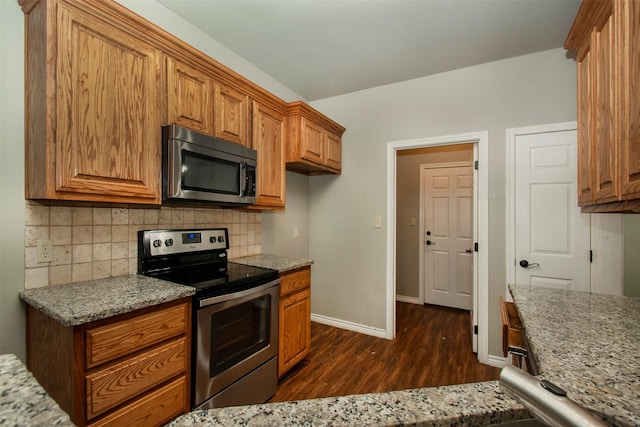 kitchen featuring stainless steel appliances, brown cabinetry, and backsplash