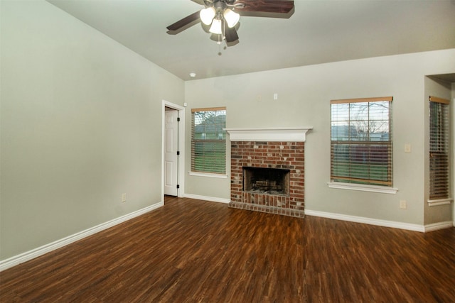 unfurnished living room with ceiling fan, a brick fireplace, wood finished floors, and baseboards