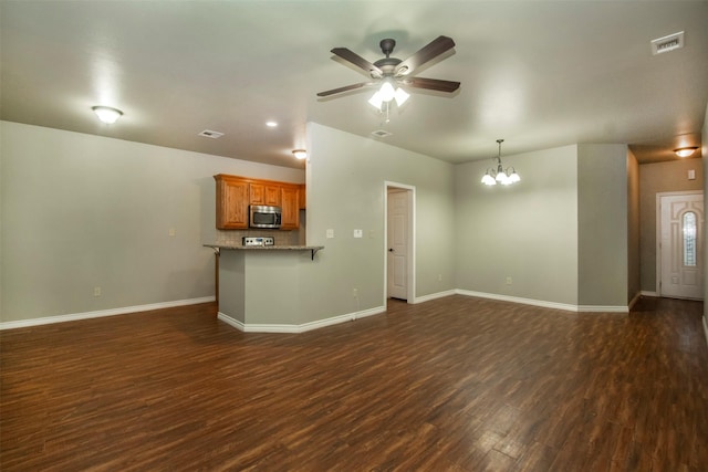 unfurnished living room featuring baseboards, visible vents, dark wood-type flooring, and ceiling fan with notable chandelier