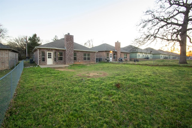 back of property with a fenced backyard, a yard, brick siding, and a patio