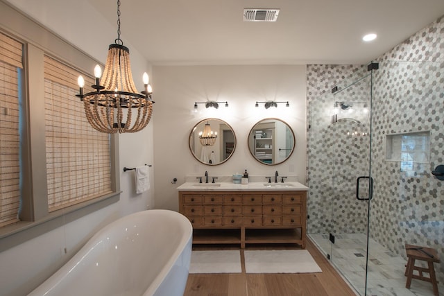 bathroom with visible vents, a freestanding bath, a stall shower, a sink, and wood finished floors