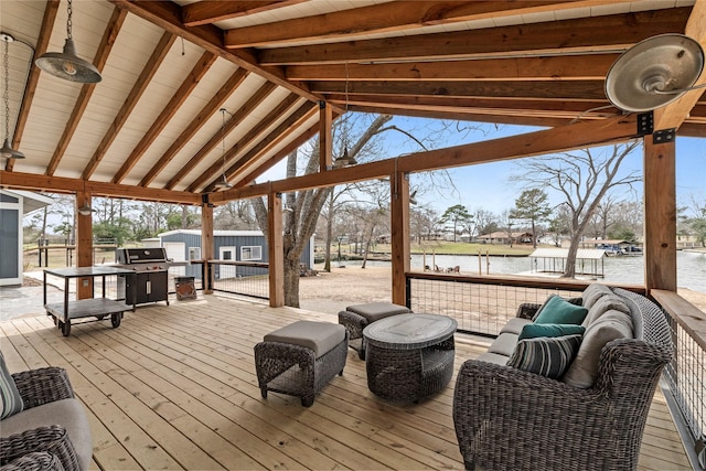 deck featuring an outdoor hangout area, a water view, a grill, and an outbuilding