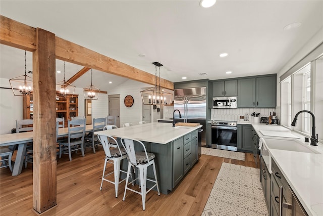 kitchen with appliances with stainless steel finishes, light wood-style flooring, and a notable chandelier