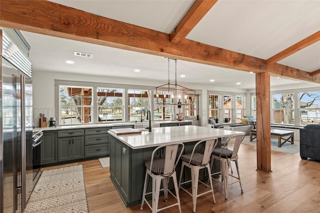 kitchen featuring gray cabinetry, visible vents, open floor plan, appliances with stainless steel finishes, and beam ceiling