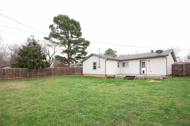 rear view of house featuring a lawn and a fenced backyard