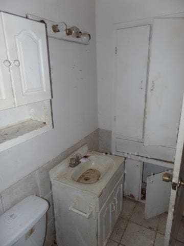 half bath featuring tile patterned flooring, vanity, and toilet